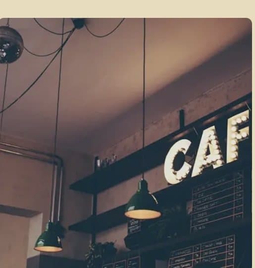 Vintage CAFÉ marquee letters glowing above a dark coffee shop interior