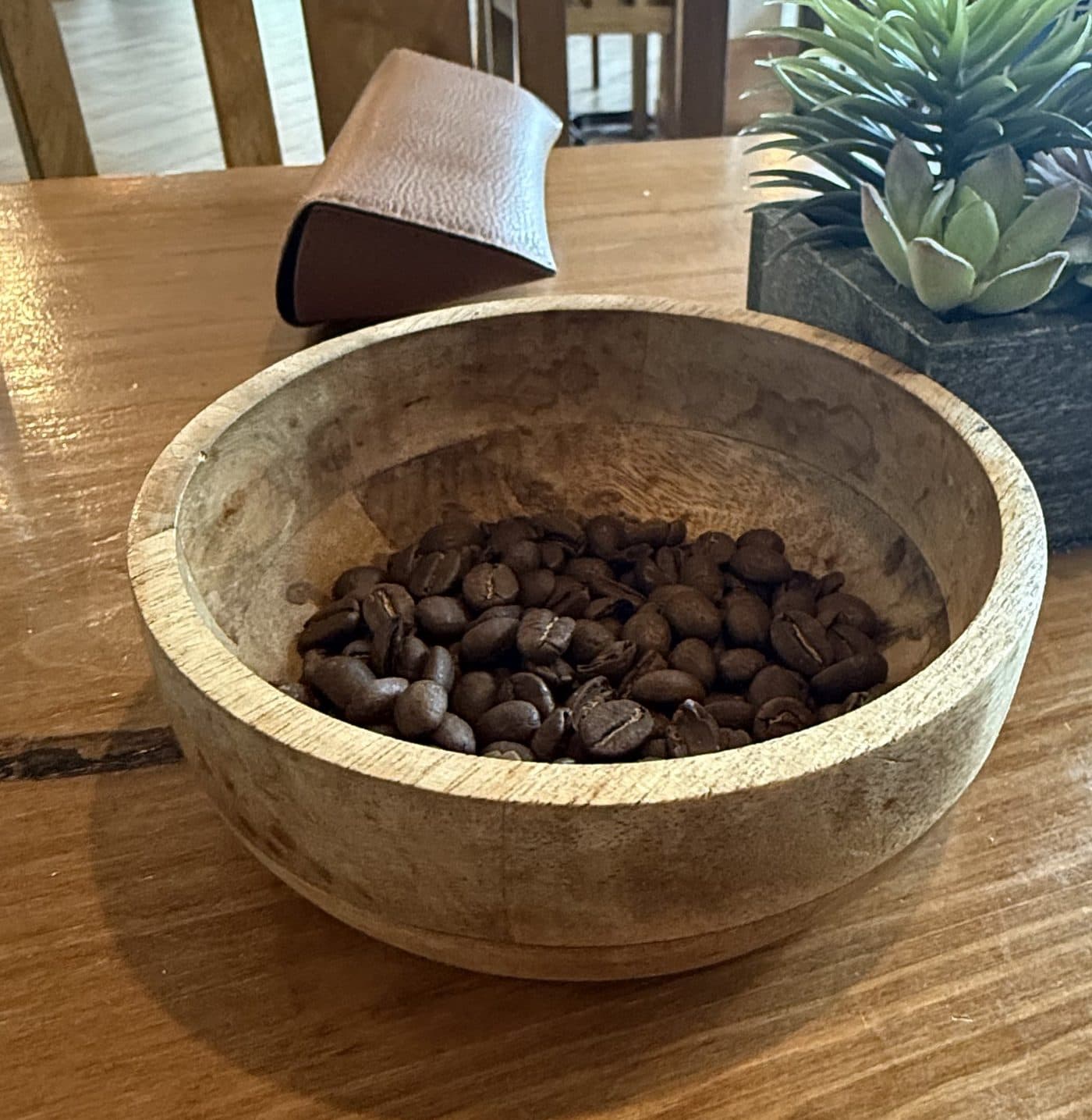 Wooden bowl of fresh coffee beans on a wooden table
