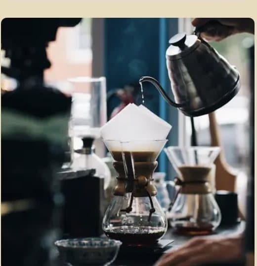 Pour-over coffee being prepared with a gooseneck kettle and Chemex carafe